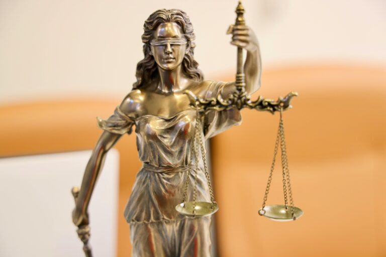 Estátua da deusa Têmis com balança da justiça, simbolizando a aplicação da lei e a responsabilidade internacional.