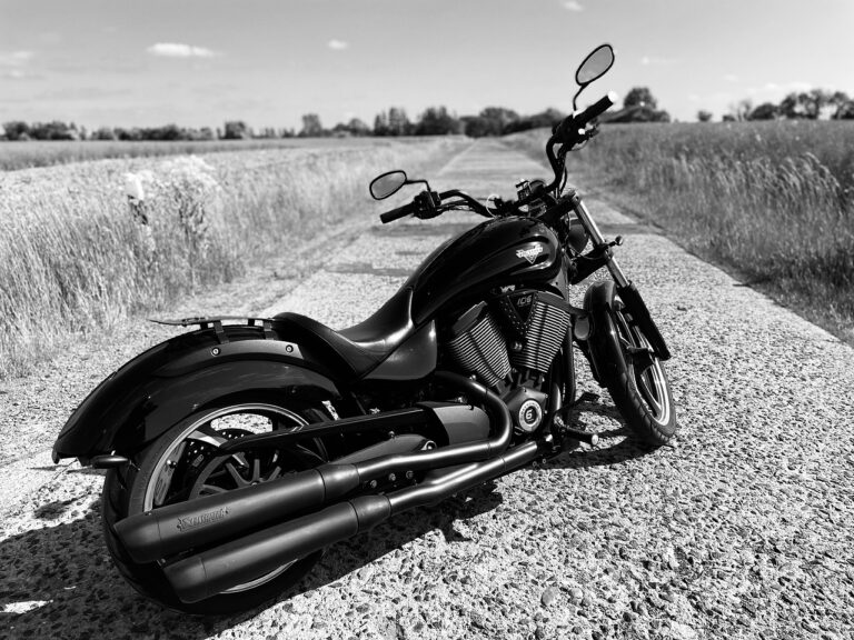 Motocicleta preta estacionada no meio de uma estrada rural deserta, em preto e branco, representando a reflexão sobre acidentes de trajeto e as consequências jurídicas de escolhas pessoais.